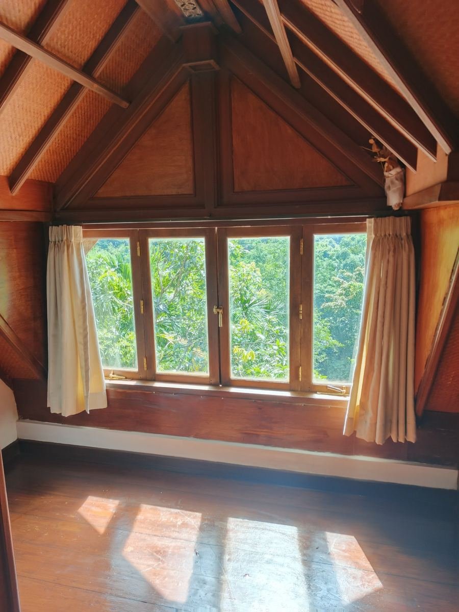 Timber attic room with cream curtains framing a garden window