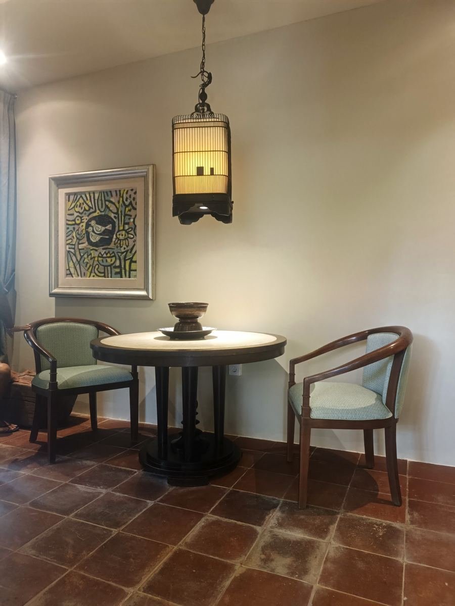 Round dining table and upholstered chairs under a rattan lantern