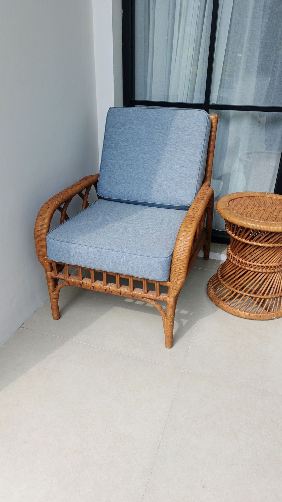 Rattan armchair with a blue cushion beside a woven side table
