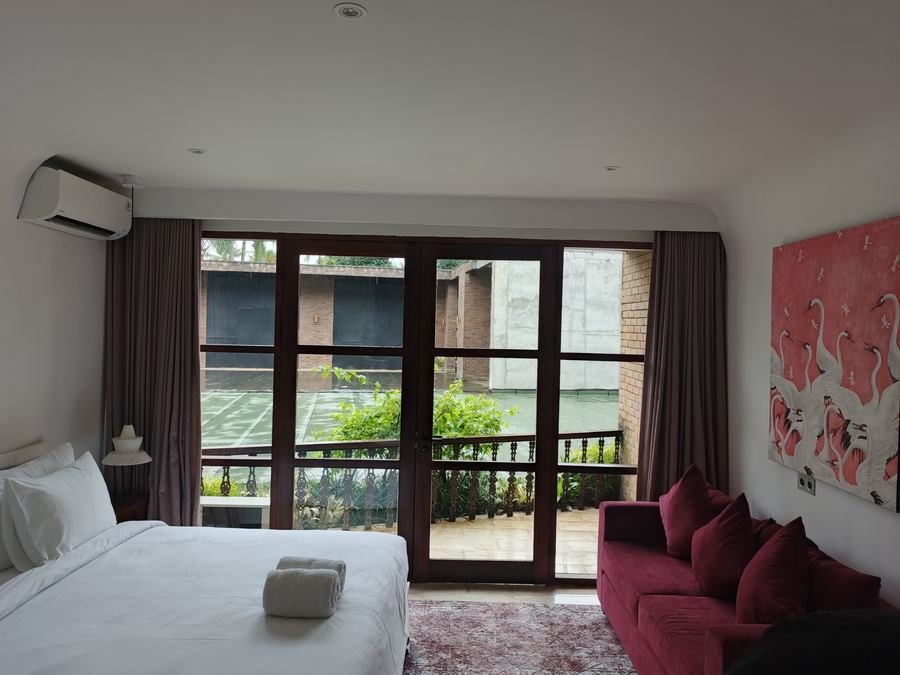 Villa bedroom with full-height curtains opening onto a garden