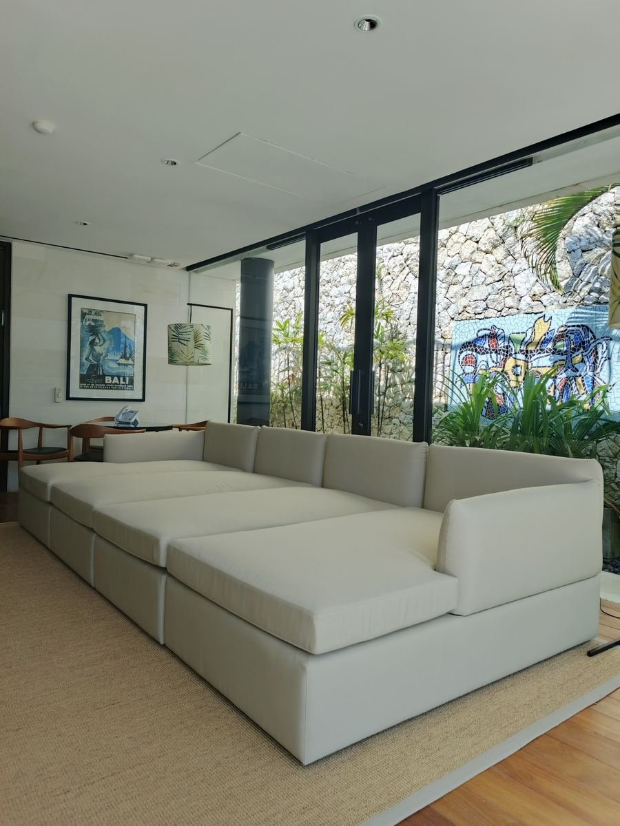 Large white modular sofa beside a glass wall and stone garden